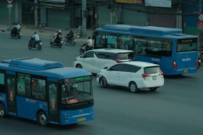 Des bus urbains bleus circulent au milieu du trafic routier pour illustrer le prix pour la location d’autocar.