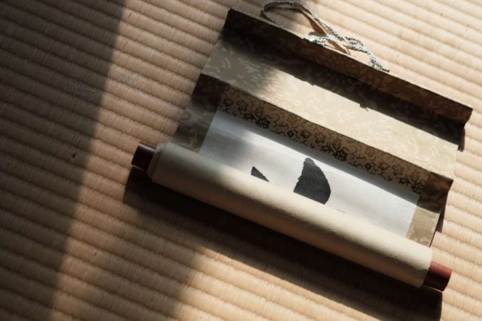 Un kakemono personnalisé traditionnel japonais partiellement déroulé sur un sol en tatami.