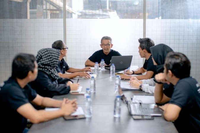 Une équipe de collaborateurs en réunion autour d'une longue table de conférence pour discuter d'un litige entre entreprises.