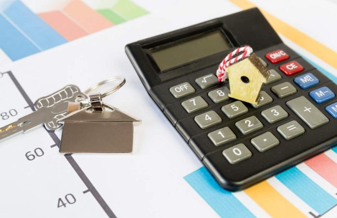 Calculatrice posée sur des graphiques financiers avec des clés de maison pour estimer le prix residence secondaire France.
