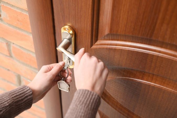 Une personne insistant sur la poignée d'une porte en bois à cause d'une clé bloquée en hiver.