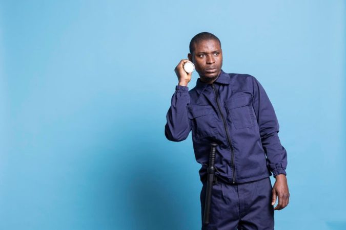 Agent de sécurité en uniforme bleu tenant une lampe de poche pour illustrer la Médaille de la sécurité intérieure.