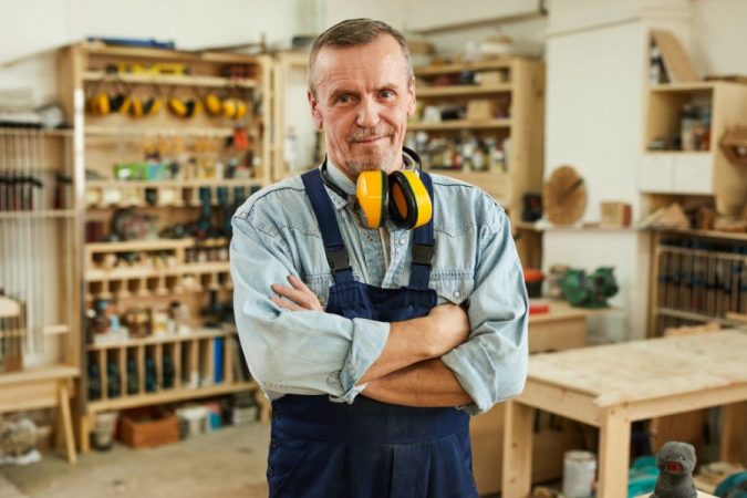 Artisan menuisier souriant dans son atelier pouvant être éligible à la médaille du travail
